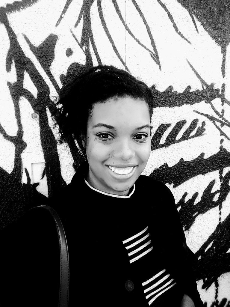 A photo of Keri smiling in front of a graffiti wall